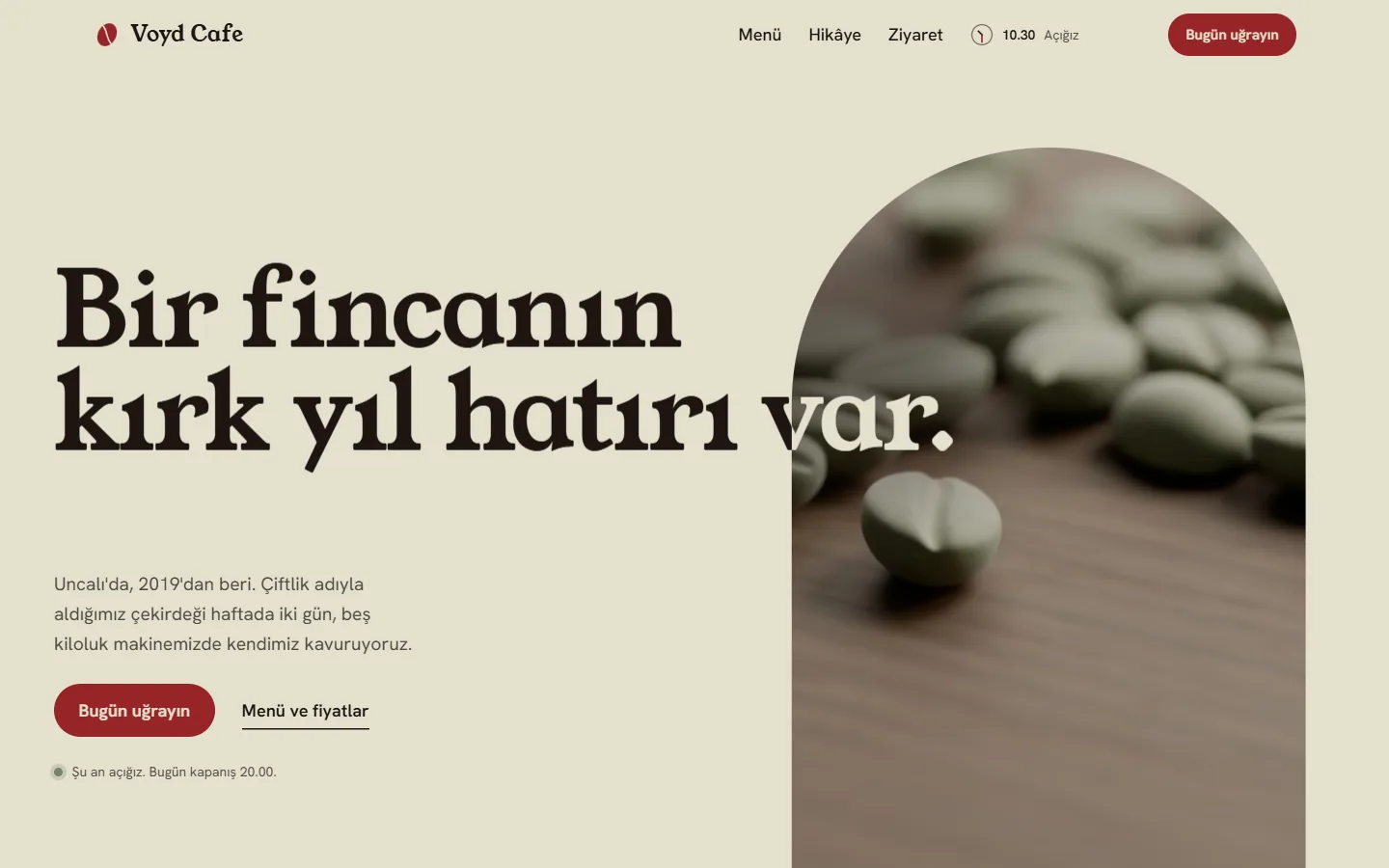 Voyd Cafe ana sayfasının açılışı, masaüstü, açık tema: solda “Bir fincanın kırk yıl hatırı var” başlığı, kısa açıklama ve “Bugün uğrayın” düğmesi; sağda kemerli bir pencerede ceviz masadaki yeşil kahve çekirdekleri. Başlığın son kelimesi kemerin üstüne taşıyor; üst çubukta küçük bir saat var.