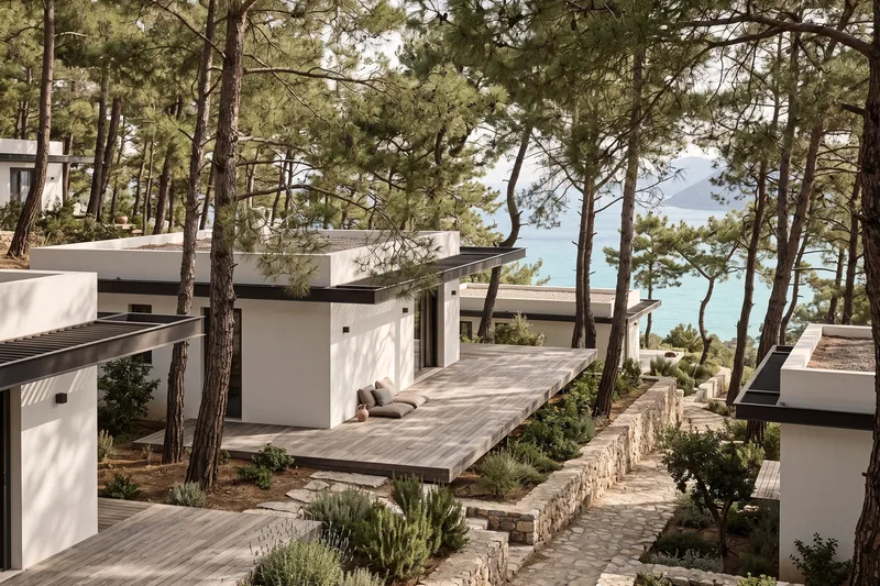 Single-storey flat-roofed villas among pine trees.